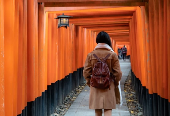 A girl wearing a backpack walking along a path, facing away from the camera