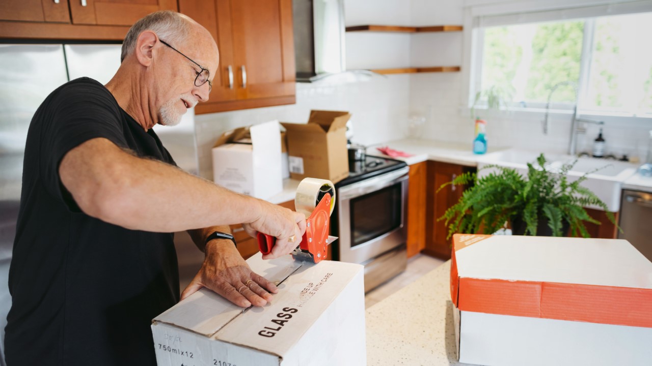 Older man packing boxes in kitchen