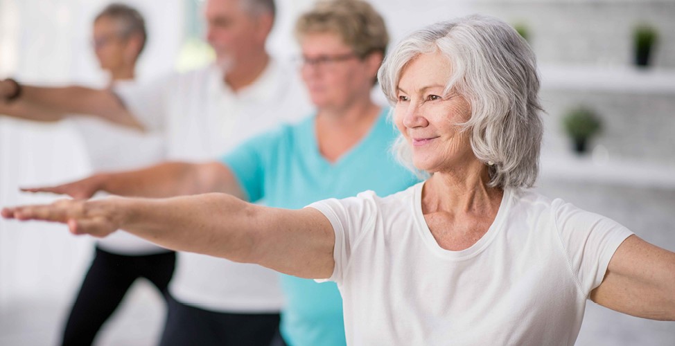 Older woman smiling while doing gentle exercise such as yoga or tai chi