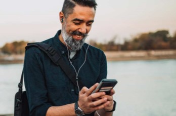 photo of a man using a phone in front of a river