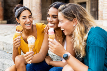 Group of female friends laughing and sharing an ice cream