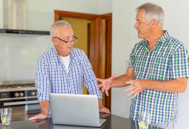 two men discussing in front of laptop