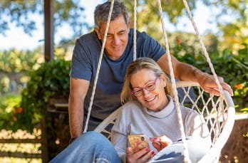 photo of a man and woman sitting outside looking at her phone