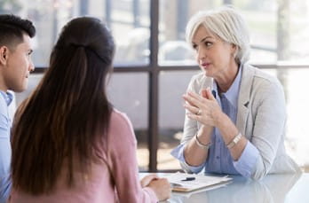 Photo of woman discussing things with a couple in a corporate setting