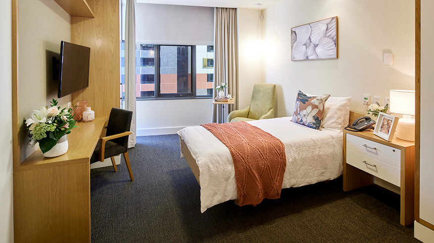 Room with bed, side table and tv on the wall