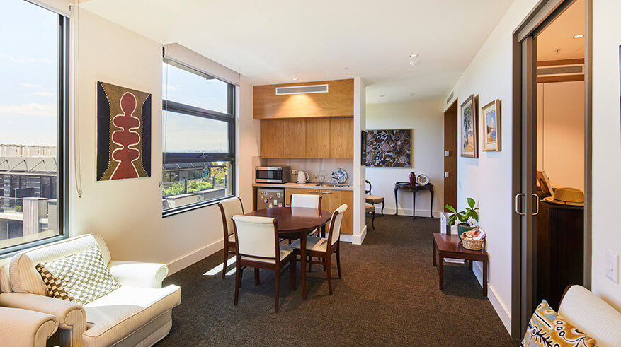 Interior of room, 4 seater dining table, grey carpet and kitchenette