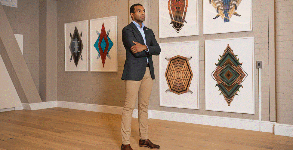 Benson Saulo standing in front of indigenous artwork