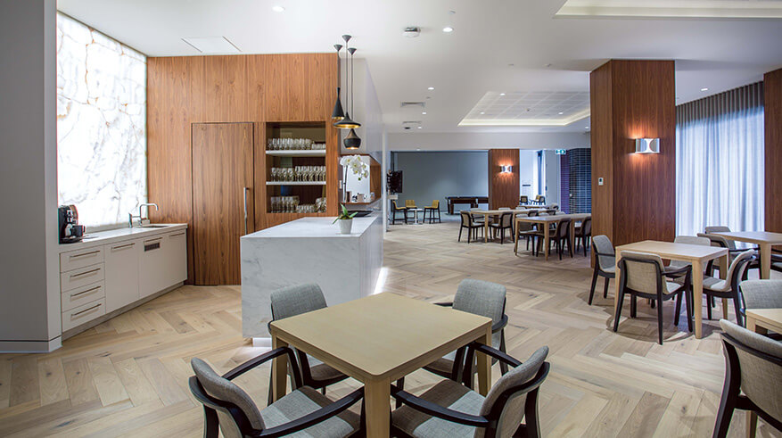 Interior of a shared kitchen space. Timber floorboards and 4 seater tables.