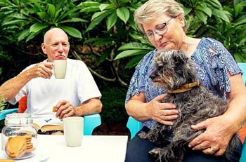 A pair of retired friends enjoying tea outside with their dog