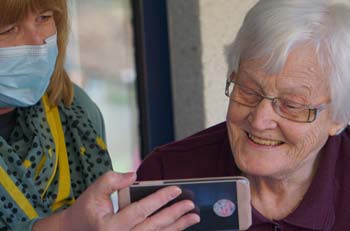 A retiree and carer using the phone smiling. 