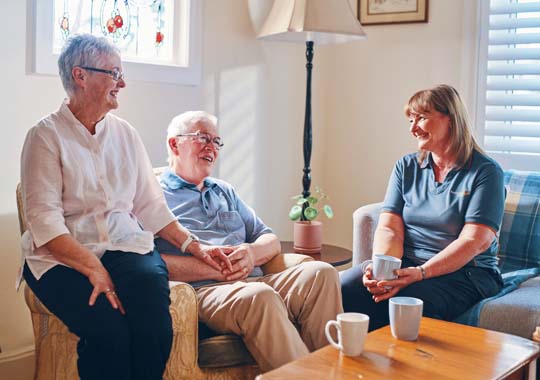 Three people sitting together in a cozy living room, engaged in conversation and enjoying each other's company.