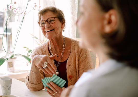  A woman smiling while engaged in conversation with another woman.