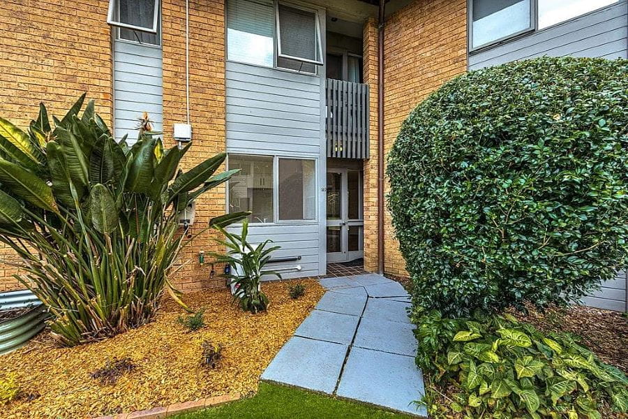 An Elderslee unit entryway surrounded by kept greenary