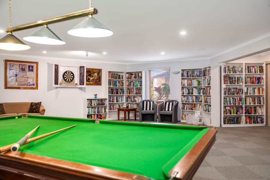 Pristine billiards table surrounded by modern bookshelves