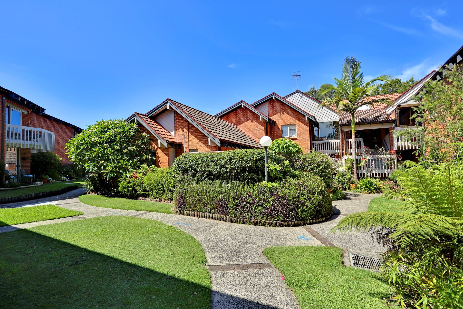 Orange brick apartments surrounded by manicured gardens and lawns