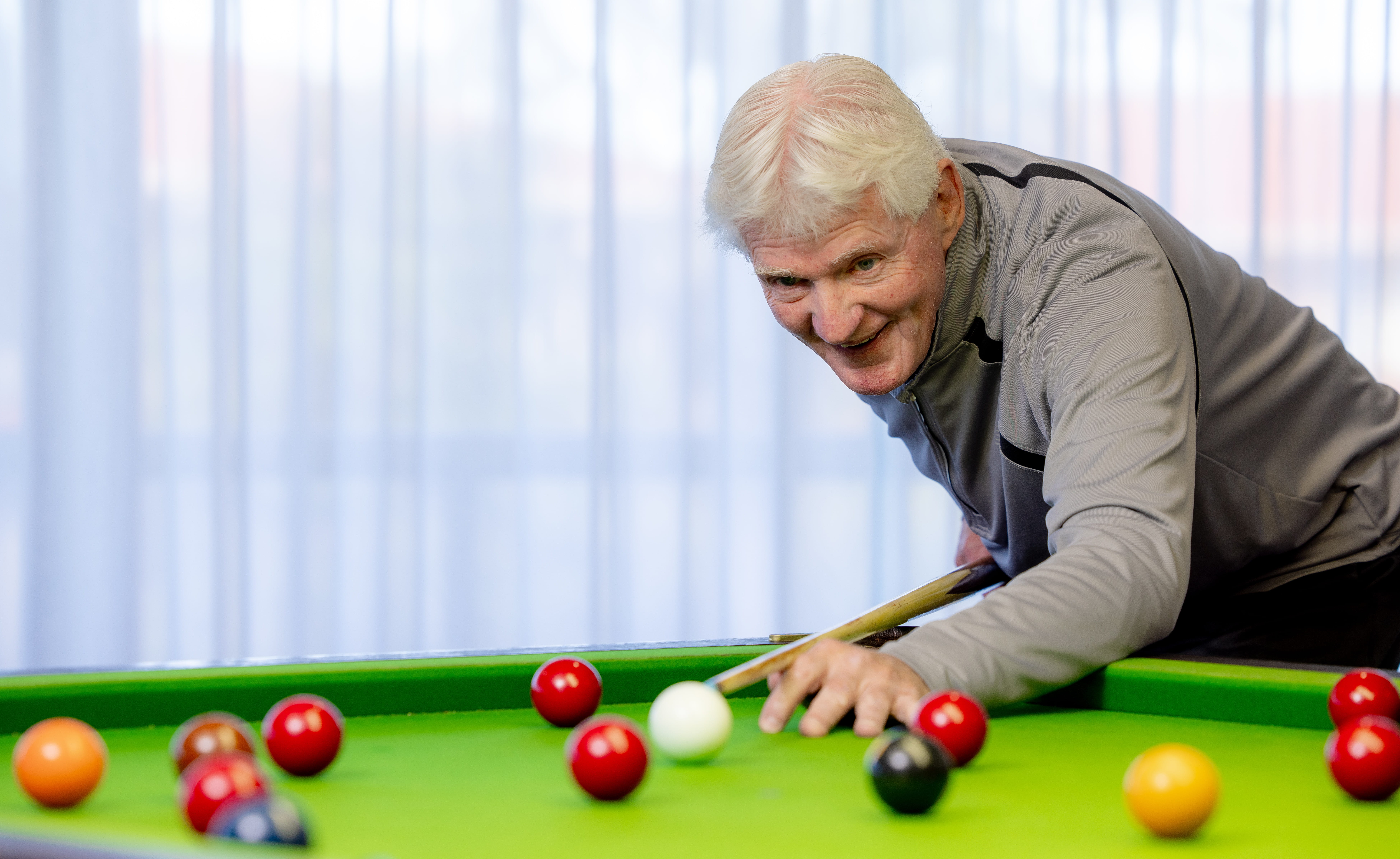 Man happily playing snooker
