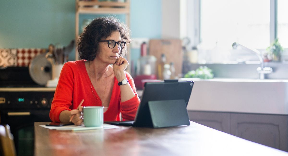 An older woman doing admin from her ipad with a furrowed expression.
