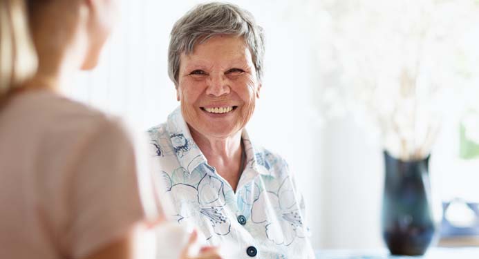 Elderly woman looking at another woman smiling