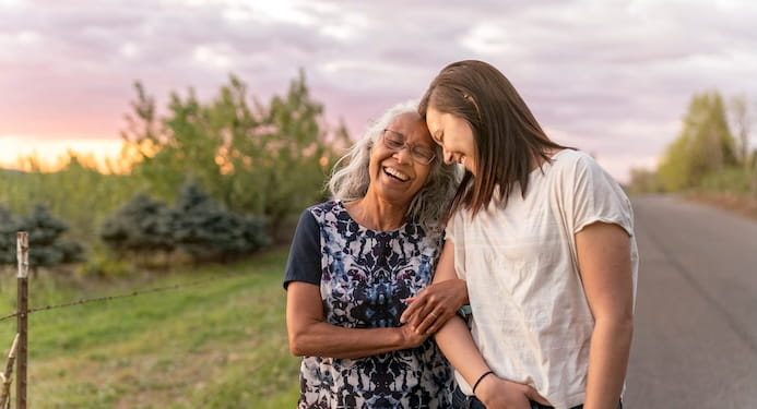 Two woman walking on the road, arm in arm, smiling