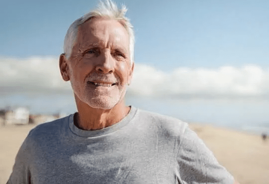 Older man standing at the beach and smiling
