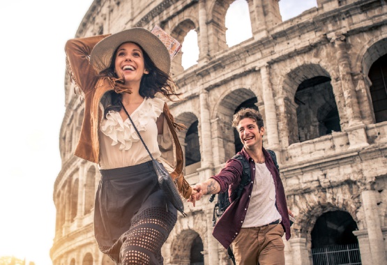 A man and a woman running in front of the Colloseum
