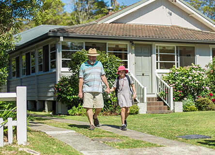Grandfather walking holding granddaughter hand, in front of house