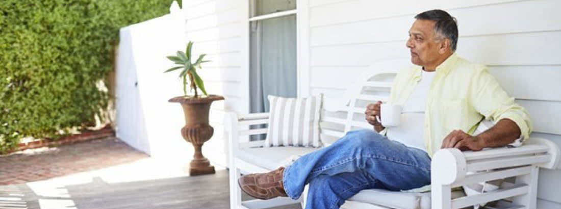 Man sitting on porch bench with a cup of tea