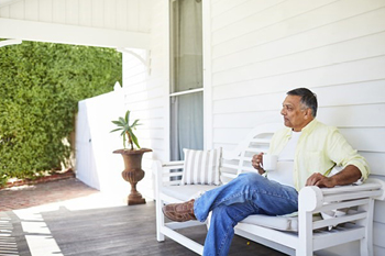 Man sitting on porch bench with a cup of tea