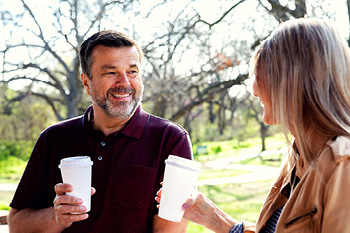 Adult male and female drinking coffee in the park