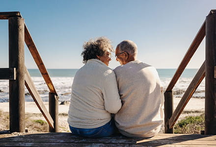 Two people, sitting on stairs looking out to the ocean.
