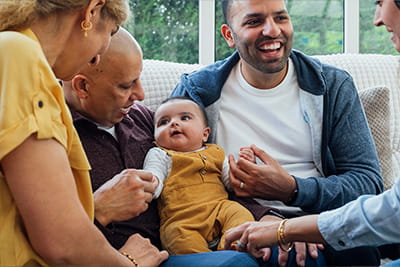 A family playing with a baby on a couch