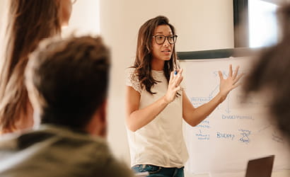 Young woman explaining concept in front of white board to a group