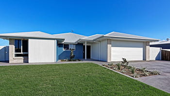 A white, single-story building with a green lawn and blue sky.