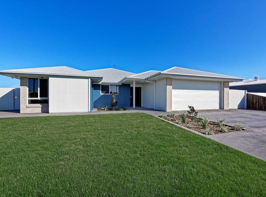 A while, single-story building with a green lawn and blue sky