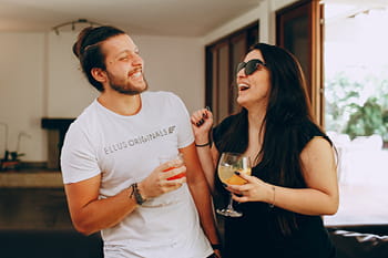 An adult male and female inside standing together and laughing