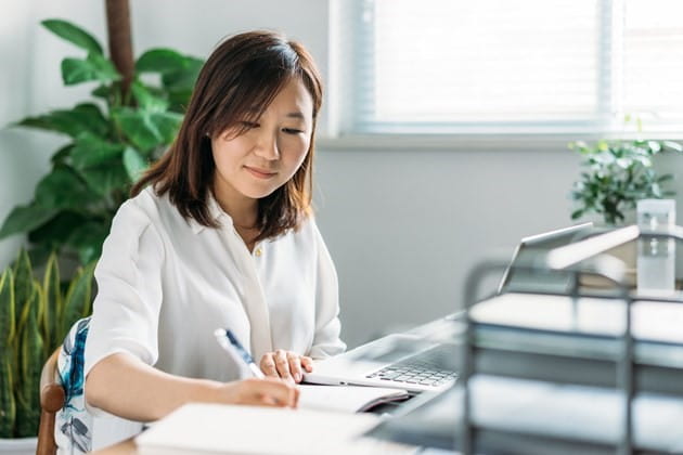 A lady sitting at a desk taking notes. 