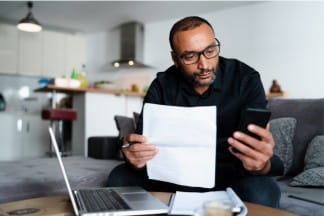 A person reading a paper in front of their laptop.