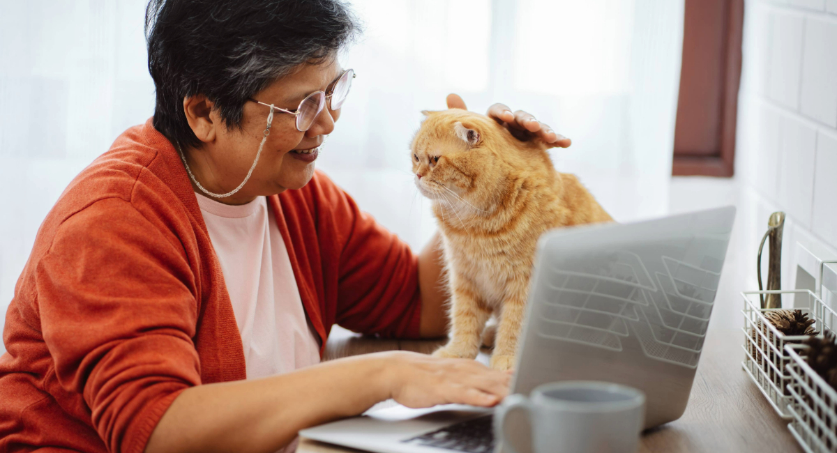 Australian Unity customer Patricia Hannan and her cat Chum sit comfortably together on the bed.