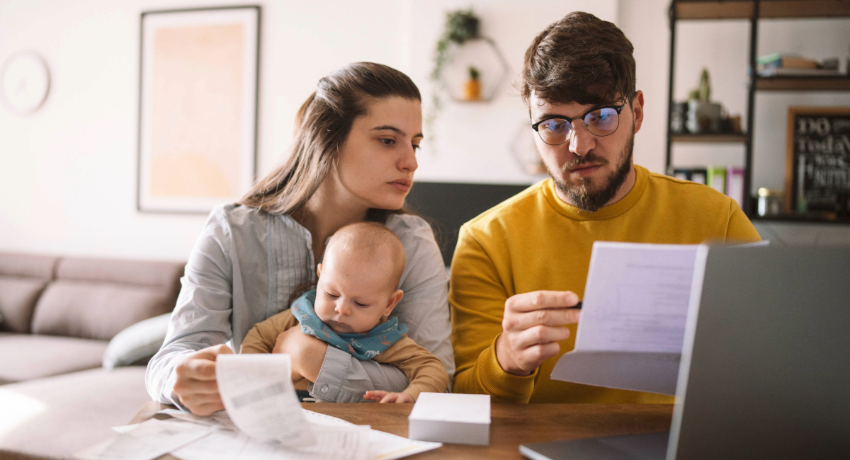 A young couple with a baby looking at financial documents