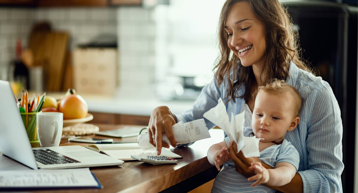 A young woman holding a baby reading financial documents