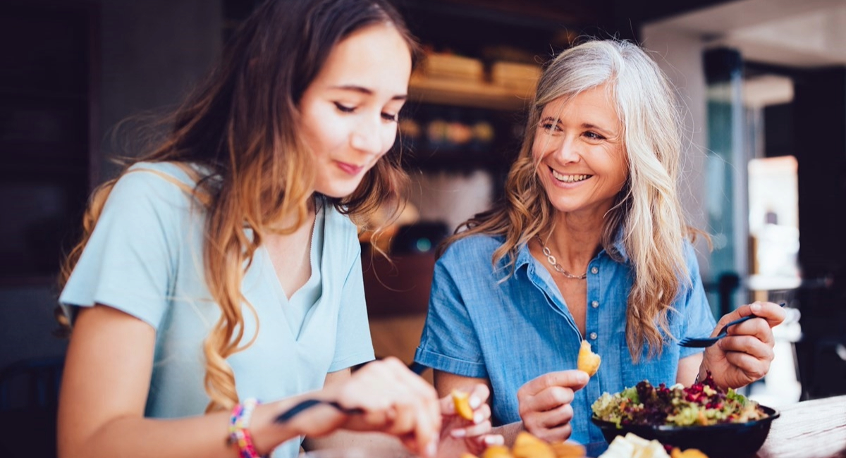 A woman smiling at another woman who is eating