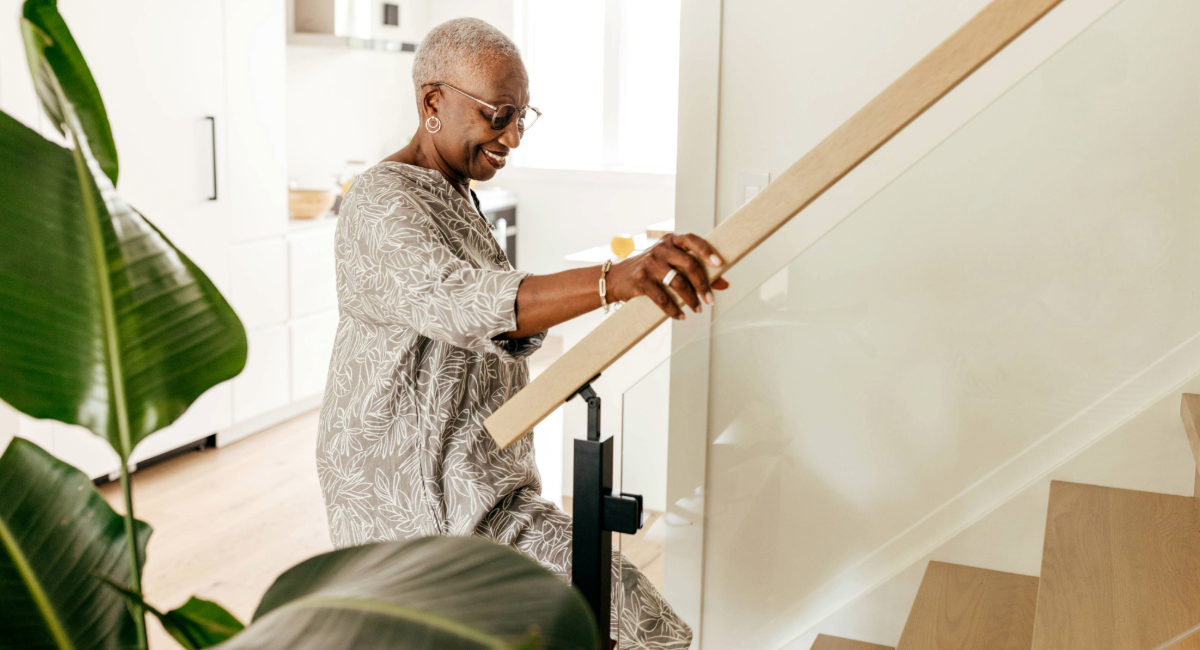 An older woman walking up the steps in her home