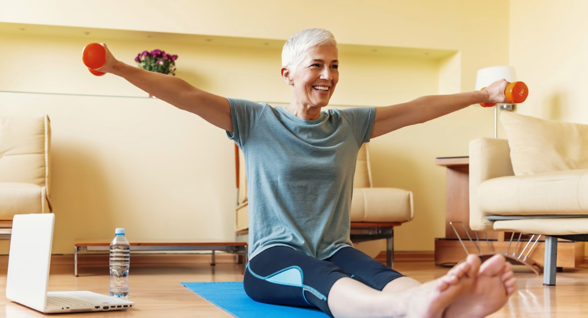 A woman exercising with weights on a yoga mat