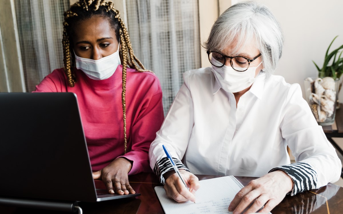 Younger woman helping older woman with computer