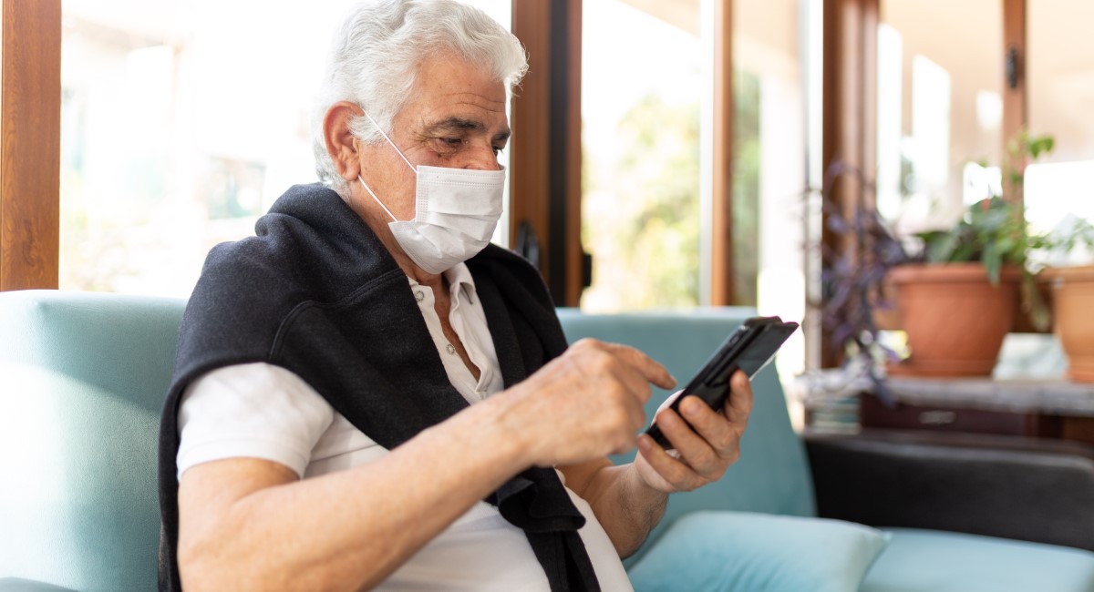 Older man wearing facemask looking at phone screen
