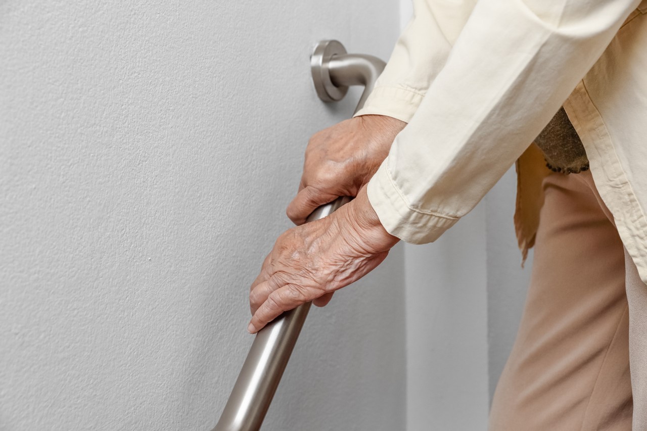 Elderly person leaning on hand rail