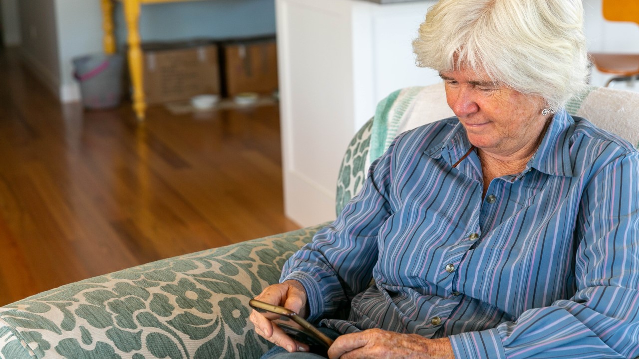 Older woman sitting in armchair, looking at phone