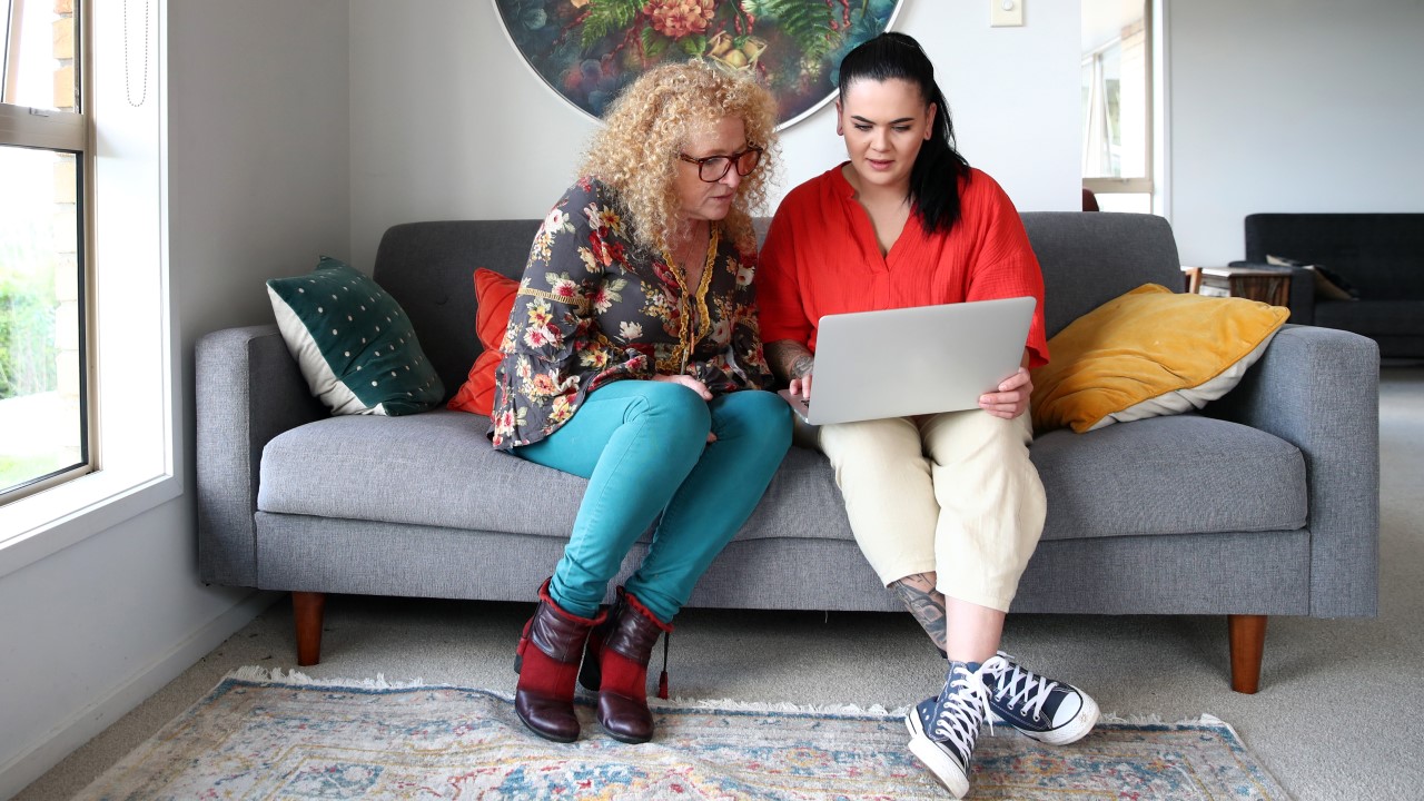 Two women on couch looking at laptop