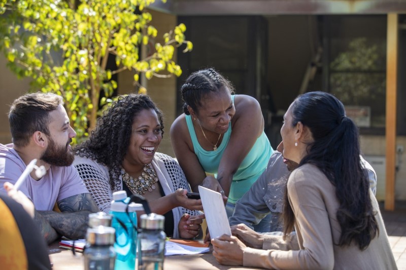 Indigenous students laughing and smiling, sitting at a table outside