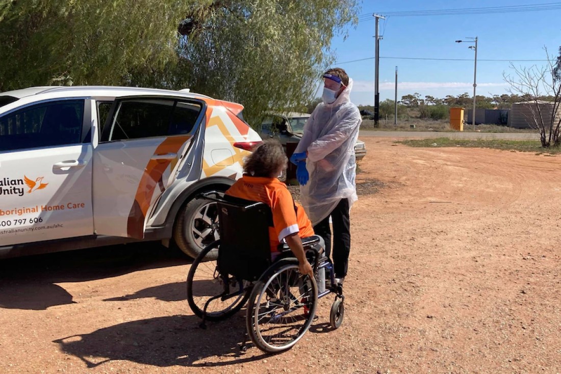 Luke Driscoll in PPE gear, helping an AHC customer in Wilcannia